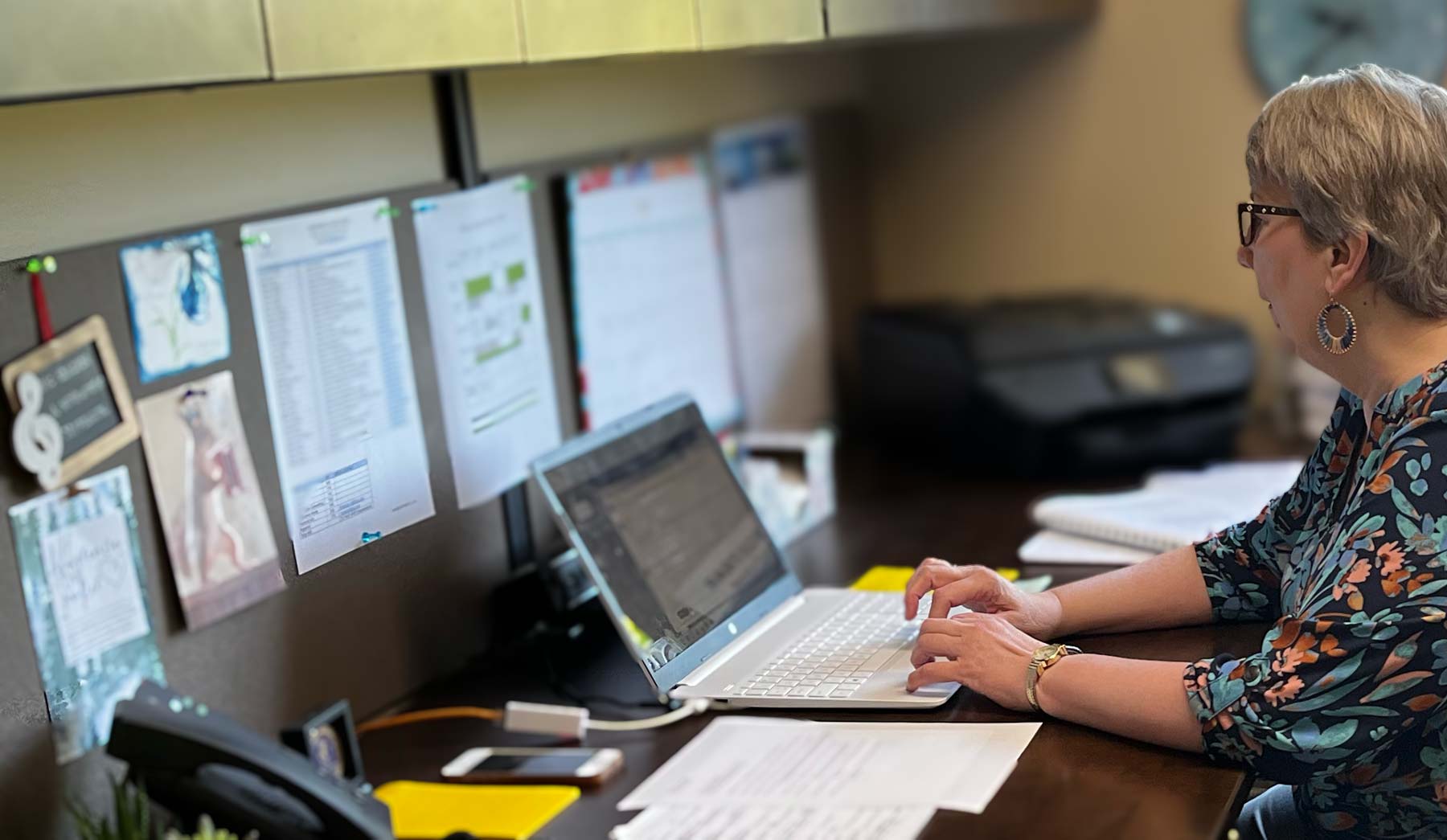 staff sitting at a desk typing on the computer in a cubicle